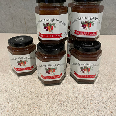 Two jars of grape jelly with visible labels on a reflective surface.
